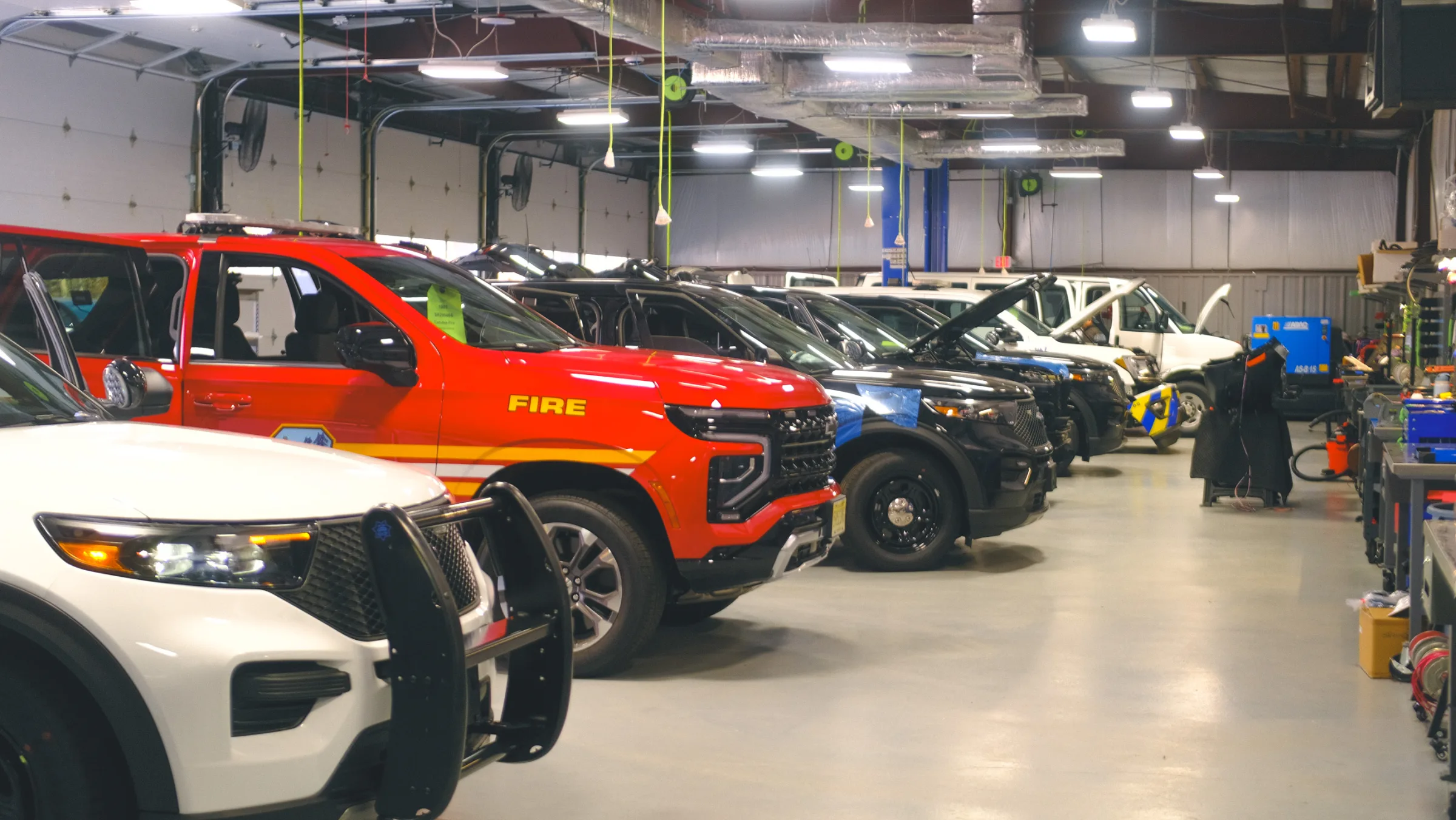 Emergency response vehicles with light bars and push bumpers inside the MEE workshop