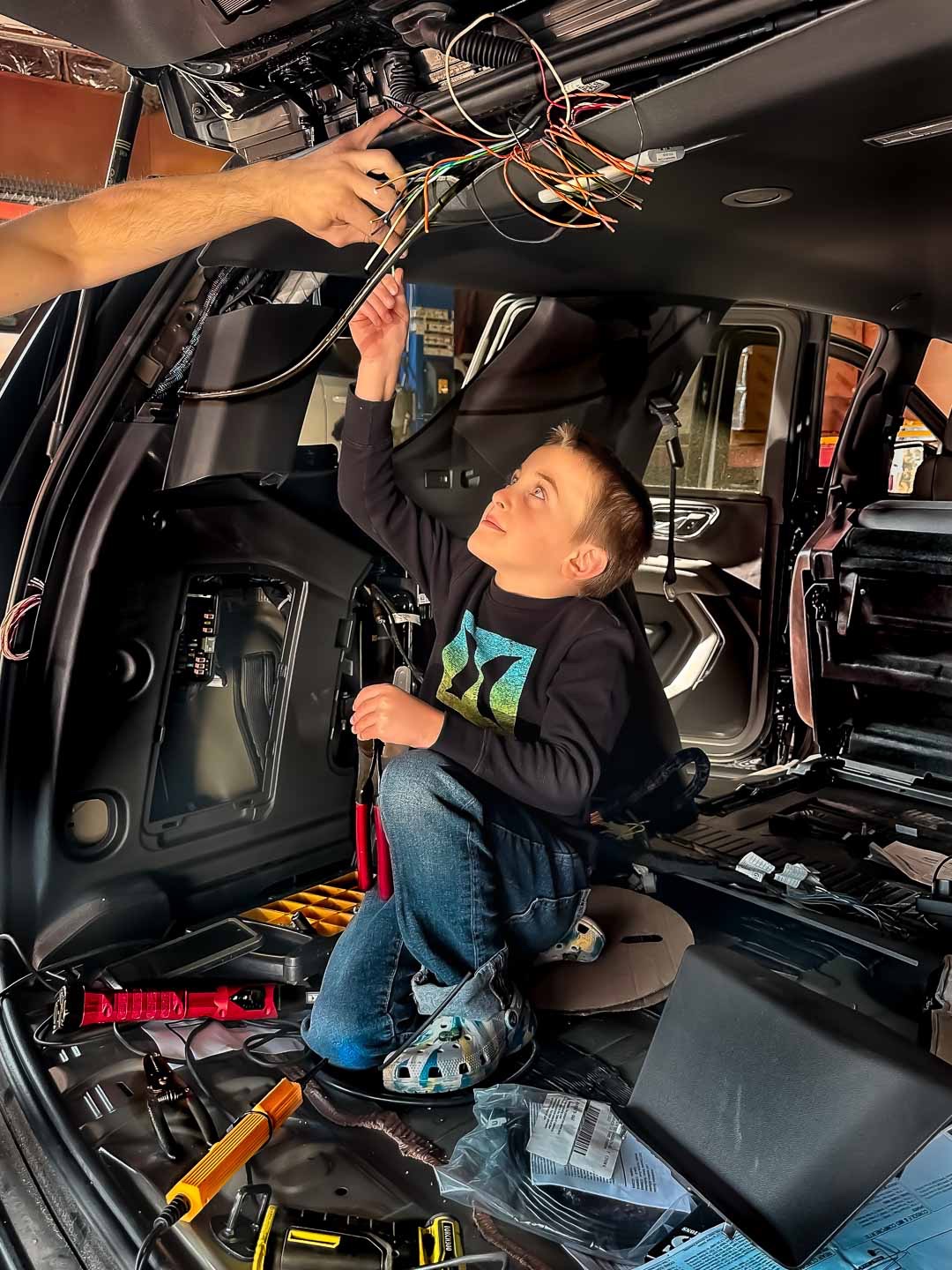 A young visitor learning about wiring inside a vehicle with an adult’s guidance